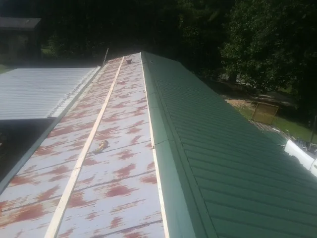Old rusted panels beside newly installed green metal roofing — Wind Damage Roof Repair by Roofing Brothers in Mays