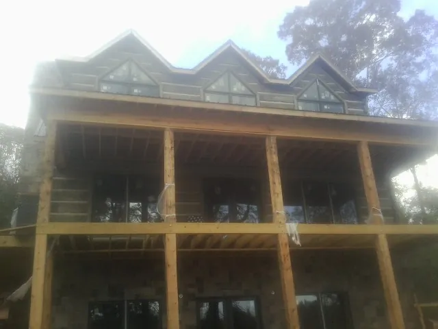 Dormers and porch framing on a large log home under construction — Roof Coating work by our crew in Mays