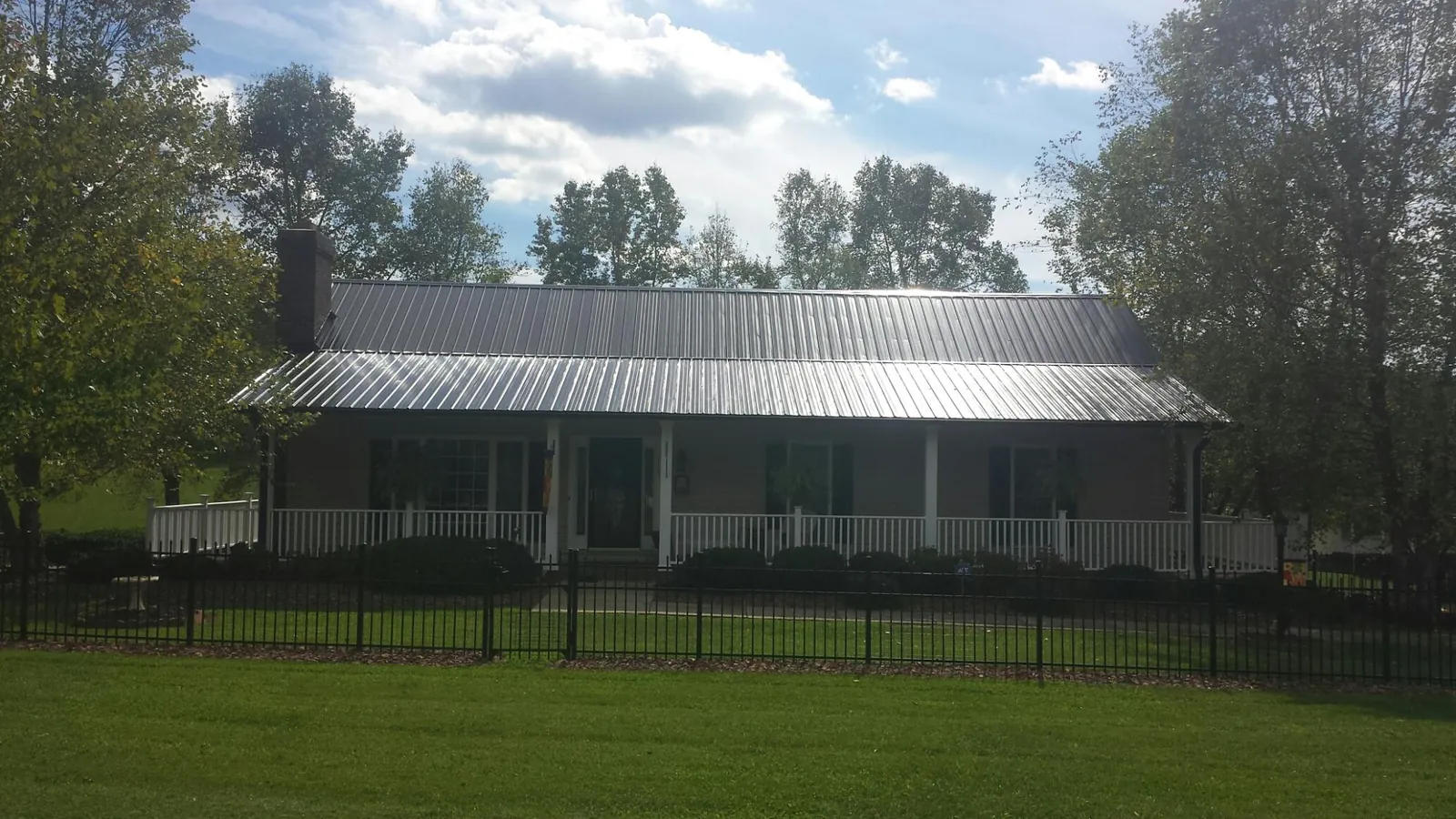 Gray metal roof on a brick ranch with a full width front porch — Gutter Guard Installation work by our crew in Mays
