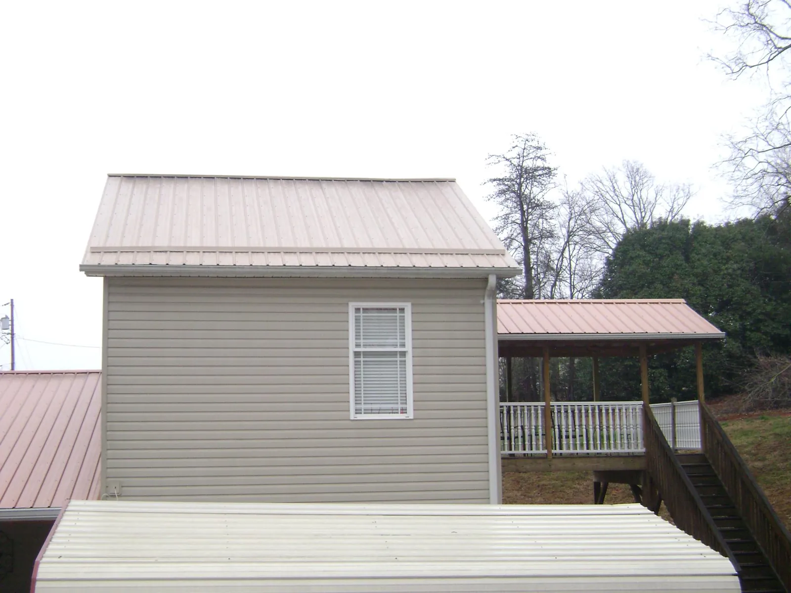 Tan metal roofs on a two story addition and attached porch, from a Roof Replacement job in Mays