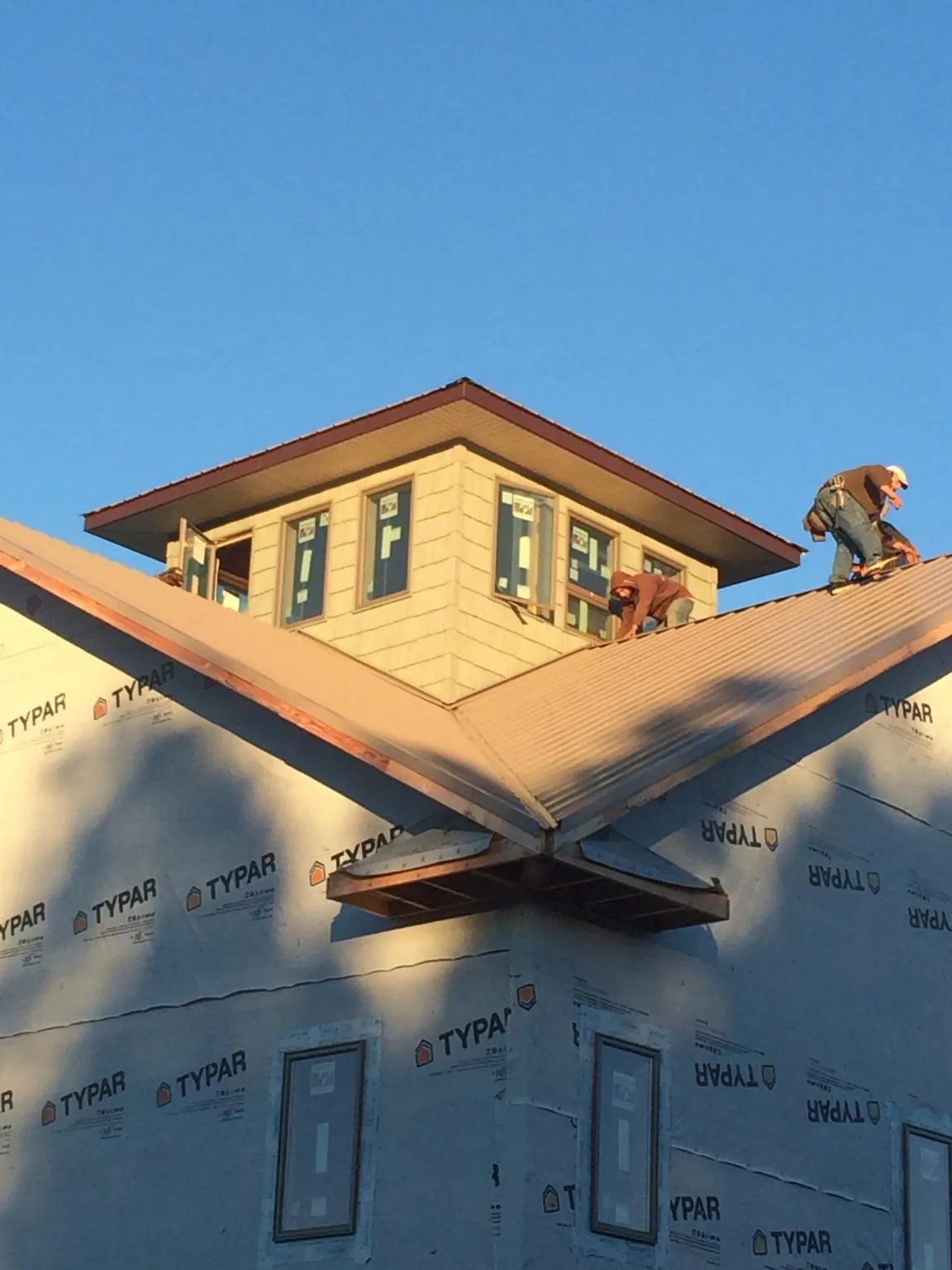 Roofers working around a rooftop cupola on a new metal roof at sunset — Roof Waterproofing in Mays by Roofing Brothers